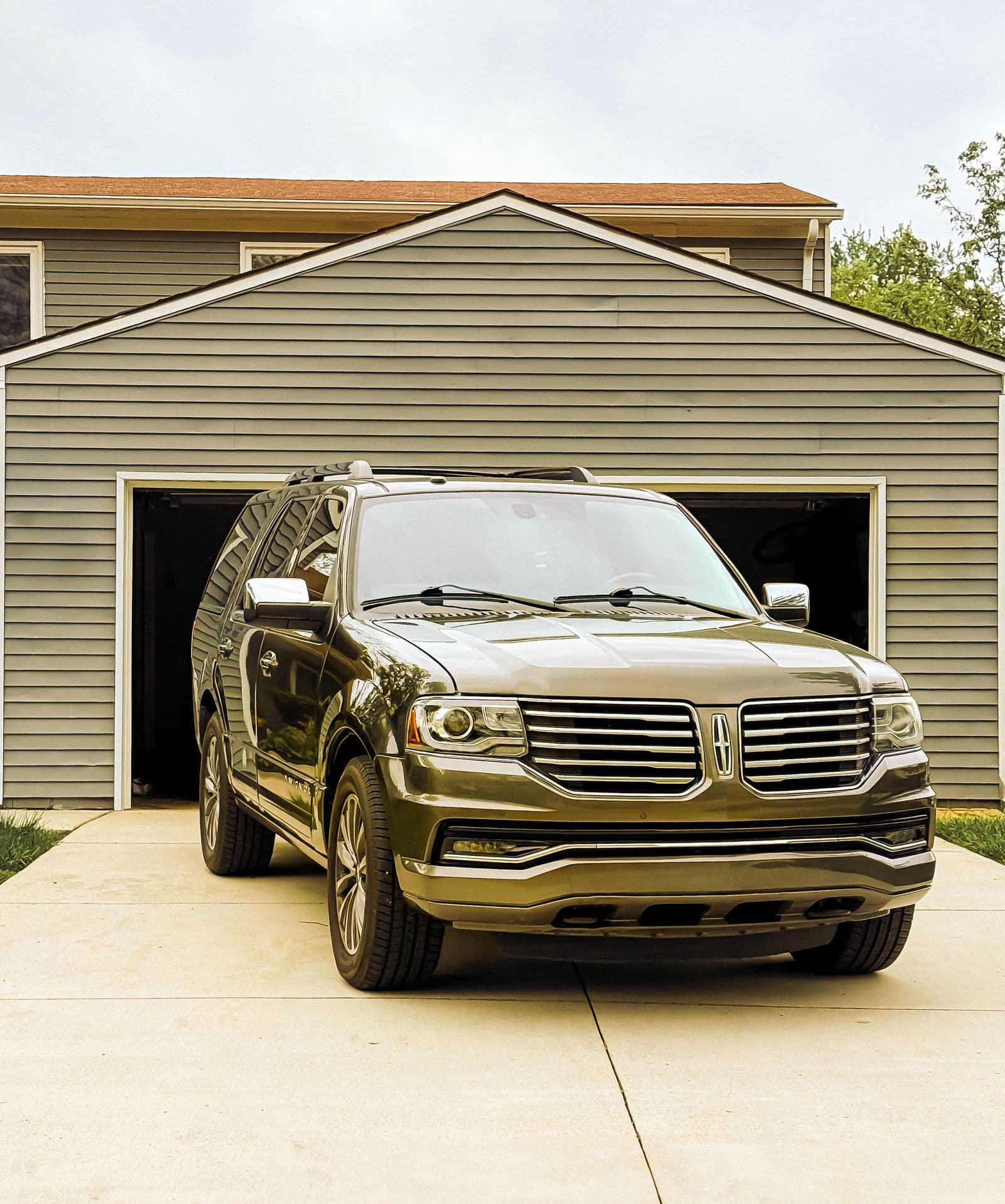 Family SUV parked in front of a two-bay suburban garage in a Kendall-style neighborhood
